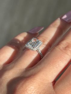 a woman's hand with a diamond ring on top of her finger and purple nail polish