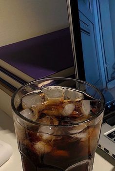 an iced beverage in a glass next to a laptop