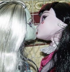 two dolls are kissing each other in the kitchen