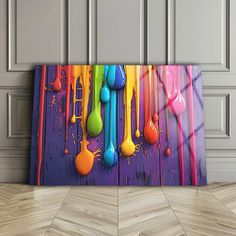 colorful spoons are hanging on the wall in front of a wooden paneled floor