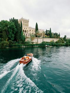 a boat is traveling down the water in front of a castle