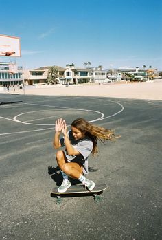 a young woman riding a skateboard on top of a parking lot next to a basketball court