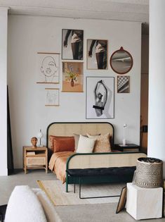 a bed sitting in a bedroom next to a wall with pictures on it and other furniture