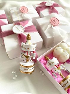 two white boxes with pink and gold ornaments in them next to some gift wrapped presents