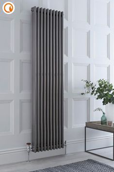 a white radiator in the corner of a room next to a table and potted plant