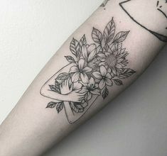 a woman's arm with flowers in a vase tattoo on the left upper arm