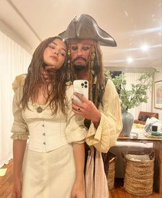 a man in a pirate costume taking a selfie with a woman wearing a white dress