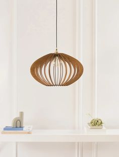 a wooden light fixture hanging over a white shelf next to a book on a table