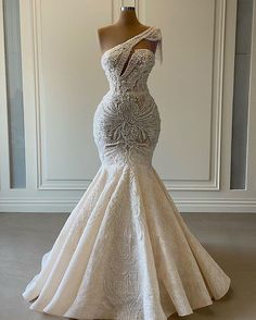 a wedding dress on display in front of a white wall with a mannequin