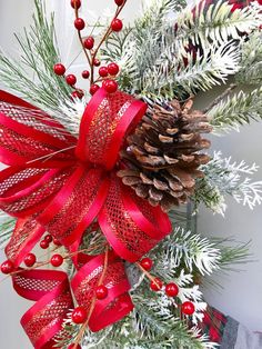 a christmas wreath with pine cones and red ribbons