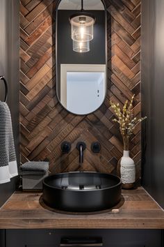 a bathroom with a round sink and wooden wall tiles on the walls, along with a mirror above it