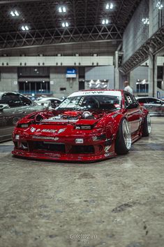 a red car parked in a garage next to other cars