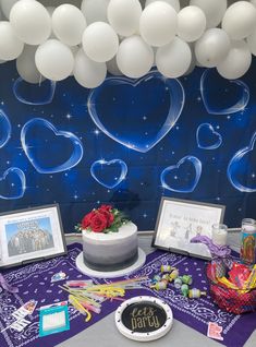 a table topped with a cake and balloons