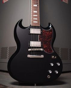 a black electric guitar sitting on top of a table