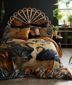 a bedroom with black walls and wooden flooring has a peacock print comforter on the bed