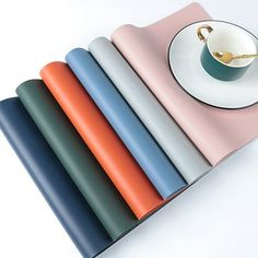 there is a cup and saucer on top of the placemats in different colors