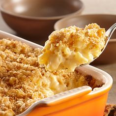 a spoon full of macaroni and cheese being lifted from a casserole dish