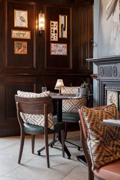 two chairs and a table in a room with wood paneling on the wall behind them