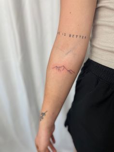 a person with a tattoo on their arm that says, it is better above the mountain