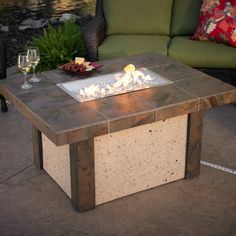 a fire pit sitting on top of a patio next to a green couch and table