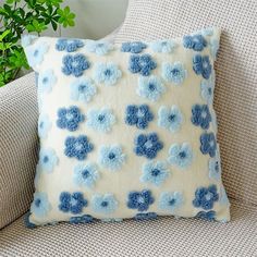 a blue and white pillow sitting on top of a couch next to a potted plant