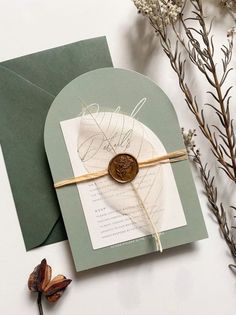 a card with a wax stamp on it next to some dried flowers and an envelope