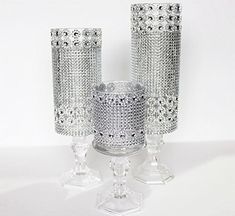 three crystal candlesticks sitting next to each other on top of a white table