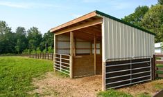 a horse barn in the middle of a grassy field