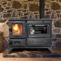 a wood burning stove sitting in front of a stone wall with a basket on the floor