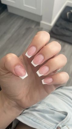 a woman's hand with french manies and white tips on the tip of her nails