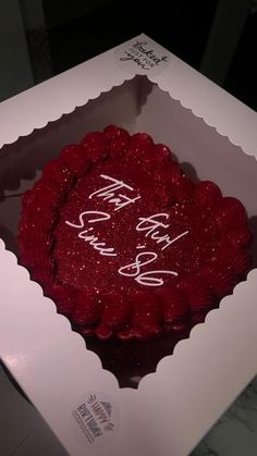 a red cake in a white box with writing on it