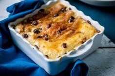 a casserole dish with cheese and raisins in it on a blue cloth