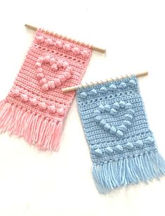 two crocheted scarves hanging on clothes pins