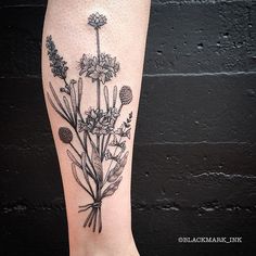 a black and white photo of a flower tattoo on the right leg, with flowers in it