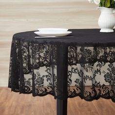 a black table cloth with white plates and flowers in a vase on the top of it