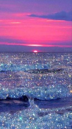 the sky is filled with stars and sparkles as the sun sets over the ocean