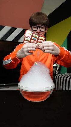 a man in an orange shirt holding up a candy bar