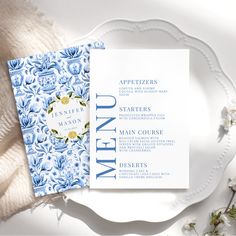 the wedding stationery is laid out on top of a white plate with blue and yellow flowers