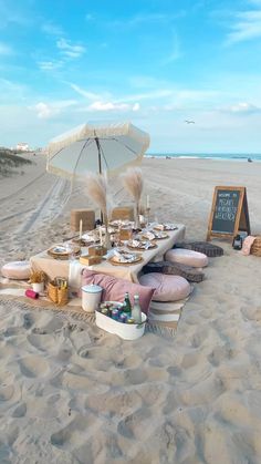 a table set up on the beach with food and drinks