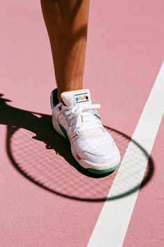 a tennis player's shoes on the court with her shadow in the ground behind them