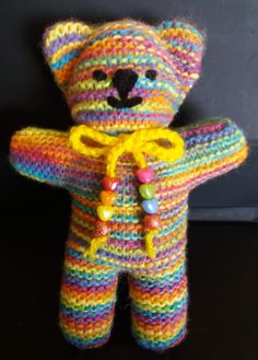 a multicolored knitted teddy bear with a yellow ribbon around it's neck