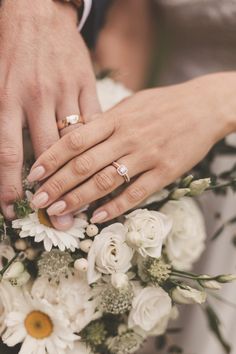 two people holding hands over a bouquet of flowers