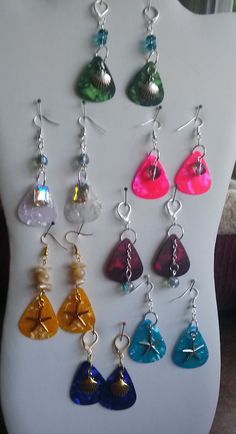 the earrings are all different colors and have dangling charms on them, as well as shells