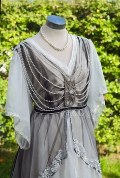 a dress with pearls on it is sitting on a mannequin headdress