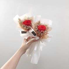 a hand holding two red roses on top of each other with hair clips attached to them