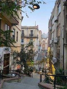 an alleyway in the city with lots of buildings on both sides and stairs leading up to it