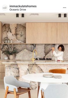 a woman standing in the middle of a kitchen next to a white table and chairs