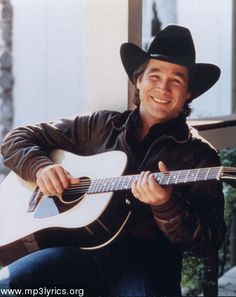 a man wearing a cowboy hat and holding an acoustic guitar in his right hand while smiling