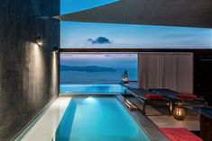 an indoor swimming pool next to a large window with the ocean in the background at night