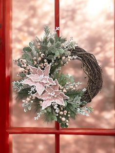 a christmas wreath on a red door with snowflakes and berries hanging from it